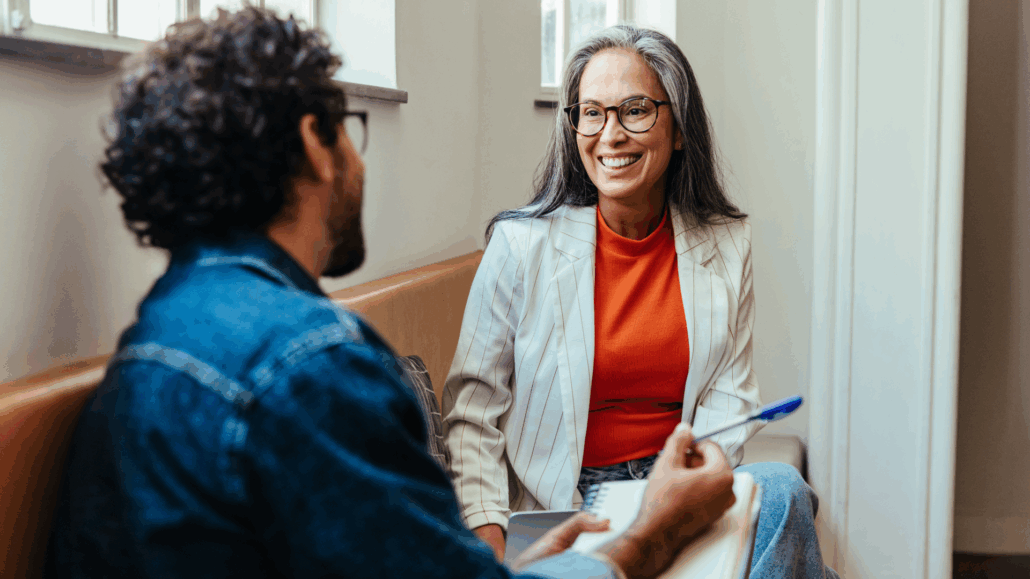 Två personer sitter och pratar på en bänk.