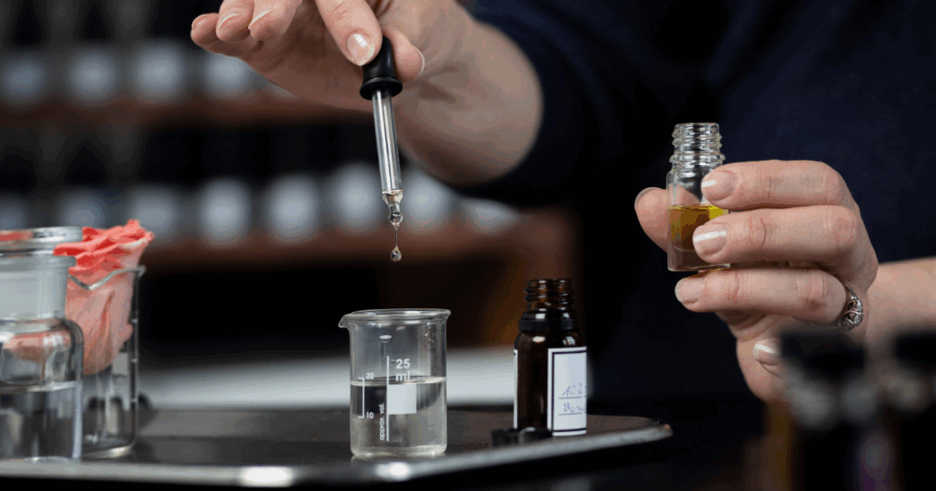 En kvinna droppar parfym i ett glas.