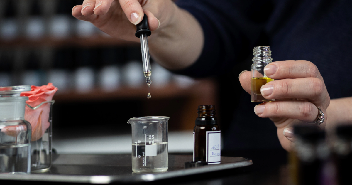 En kvinna droppar parfym i ett glas.