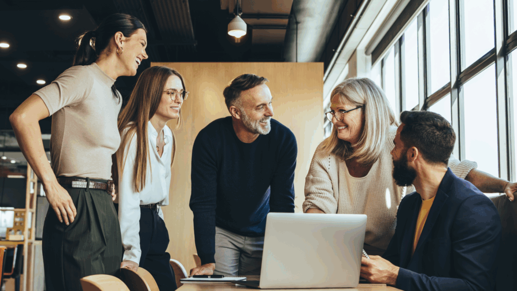 En grupp glada människor står runt ett bord.